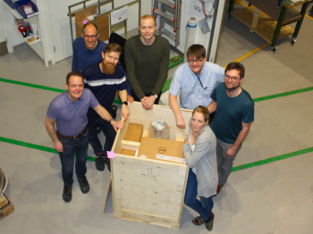 A group of people standing around a shipping crate that contains the new DA20 analyser from Scienta Omicron.  | © Scienta Omicron 